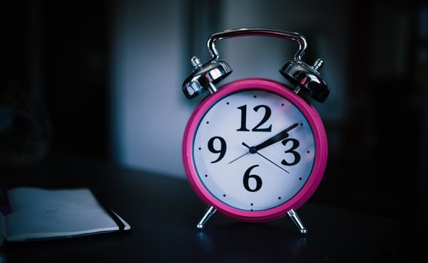 Old fashioned alarm clock with pink rim on black background (1)